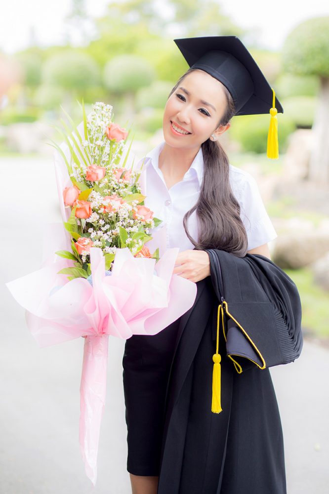 women is a Graduate holding a bouquet and smiling for the camera