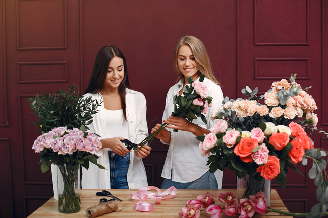 Florisr with flowers. Women makes a bouquete. Two girls working
